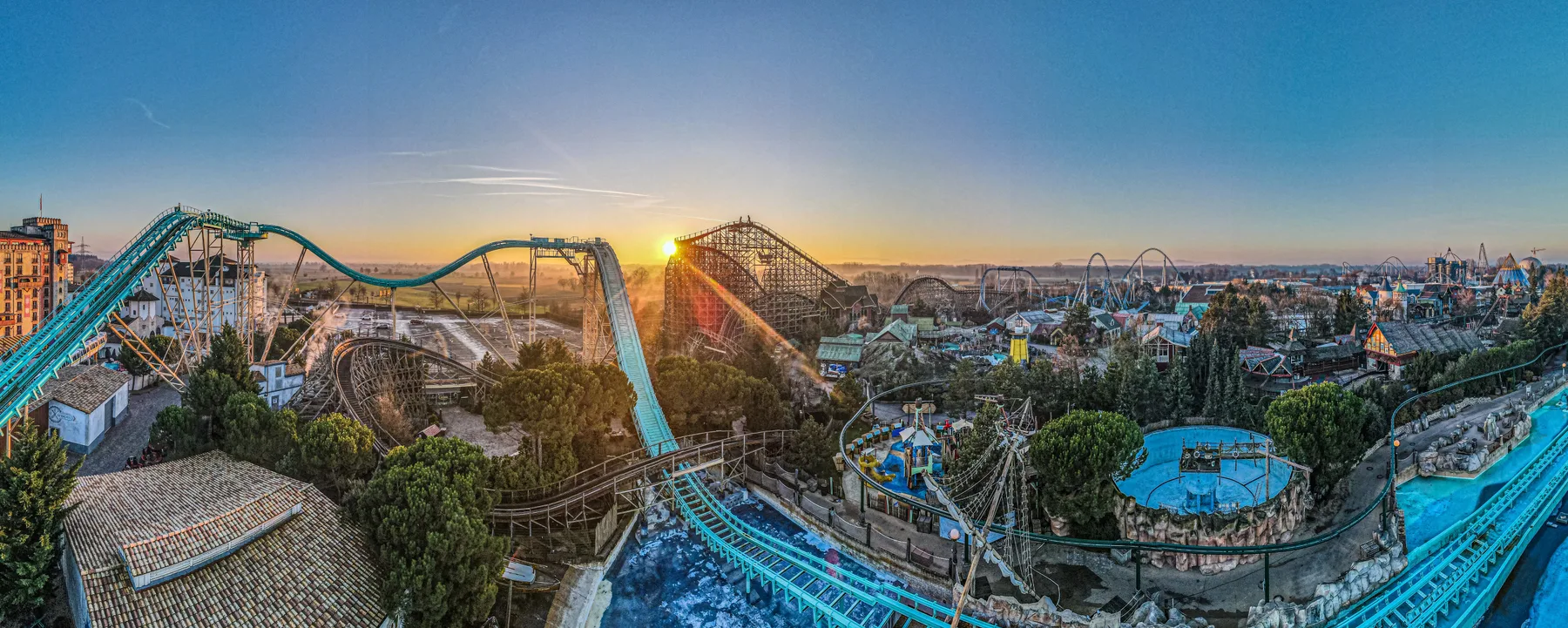 Panorama des Europa-Park bei Sonnenaufgang mit Achterbahnen und Themenbereichen.